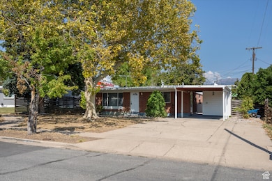 View of front of home with concrete driveway, a carport, and brick siding