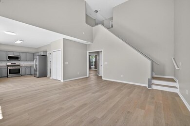 Unfurnished living room featuring light wood-type flooring, a high ceiling, and stairs