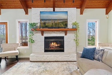 Living room featuring a stone fireplace, beam ceil