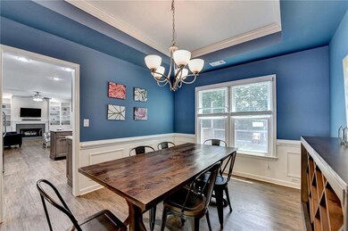 Dining room featuring ornamental molding, ceiling fan, a chandelier, a wainscoted wall