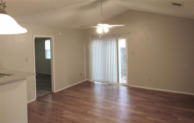 Unfurnished living room with healthy amount of natural light, dark wood-type flooring, lofted ceiling, and ceiling fan