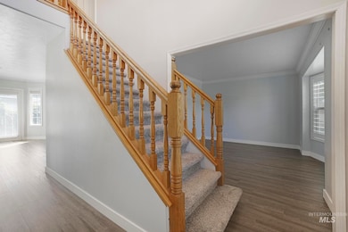 Stairs featuring wood finished floors and crown molding