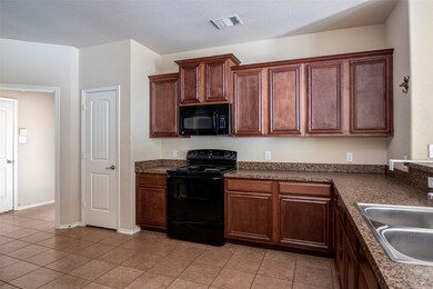 Kitchen with black appliances, light tile patterned floors, dark countertops, and a textured ceiling