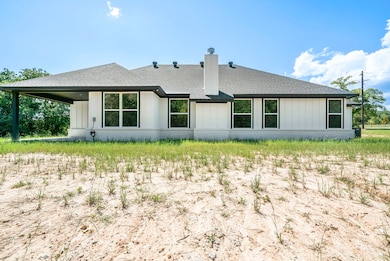 Rear view of house with a shingled roof, a chimney, and a patio