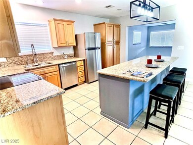 Kitchen with hanging light fixtures, a kitchen breakfast bar, stainless steel appliances, and light tile patterned floors