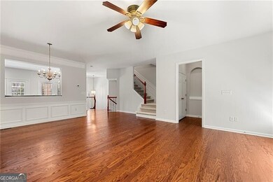 Living room featuring a ceiling fan, a chandelier, wood finished floors, and stairs