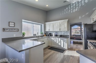 Kitchen with a sink, white cabinets, a peninsula,