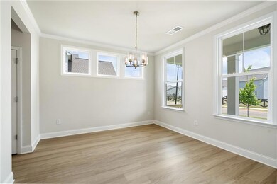 Unfurnished room with a chandelier, light wood-type flooring, crown molding, and baseboards