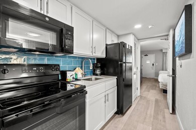 Kitchen featuring sink, backsplash, white cabinets