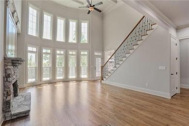 Unfurnished living room with a ceiling fan, ornamental molding, stairway, baseboards, and a fireplace