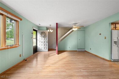 Unfurnished living room featuring light wood-style flooring, a chandelier, and a ceiling fan