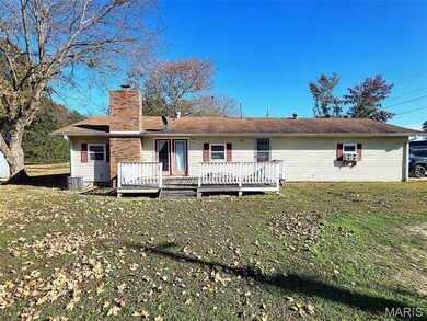 Back of property with a chimney, a yard, a wooden deck, and cooling unit