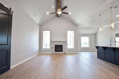 Unfurnished living room with light hardwood / wood-style floors, a fireplace, a barn door, high vaulted ceiling, and ceiling fan