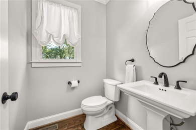 Half bath featuring baseboards and wood finished floors