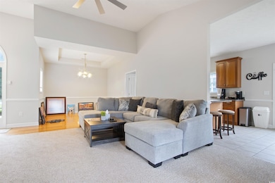 Living room featuring a chandelier, light colored carpet, and a ceiling fan