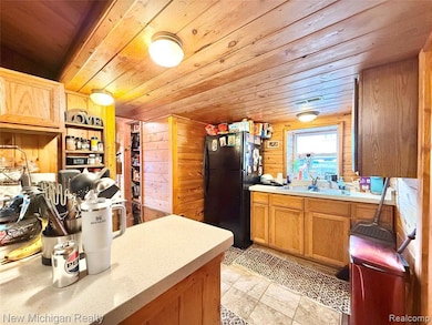 Kitchen with freestanding refrigerator, wooden ceiling, and wood walls