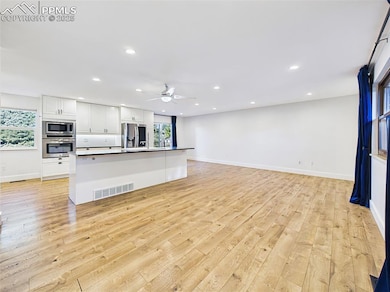 Expansive open-concept layout features a sleek modern kitchen with stainless steel appliances, crisp white cabinetry, and an oversized island ideal for entertaining.