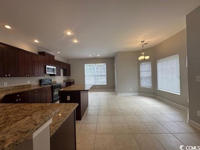 Kitchen featuring dark brown cabinetry, black electric range oven, light tile patterned floors, light stone counters, and stainless steel microwave