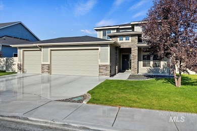 Prairie-style home with stone siding, an attached garage, a front lawn, and concrete driveway