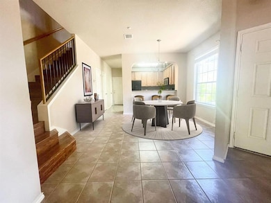 Tiled dining room with a chandelier, stairway, an