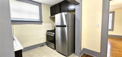 Kitchen featuring stainless steel appliances, exhaust hood, dark cabinets, and baseboards