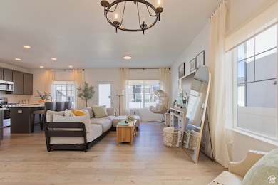 Living room featuring light wood-type flooring, recessed lighting, and a chandelier