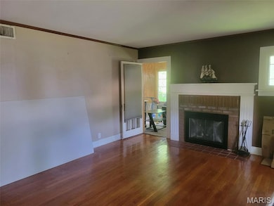 Unfurnished living room featuring wood finished floors, a fireplace, plenty of natural light, and ornamental molding