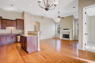 Kitchen with light stone countertops, light wood finished floors, arched walkways, a chandelier, and open floor plan