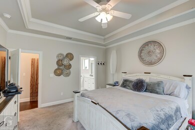 Carpeted bedroom featuring ceiling fan, a tray cei