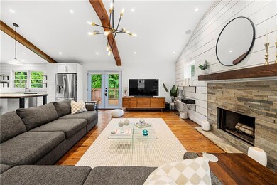 Living area featuring plenty of natural light, light wood finished floors, a fireplace, a chandelier, and wooden walls