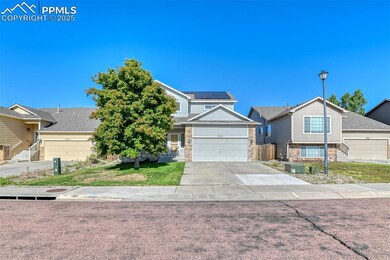 View of front of home featuring concrete driveway, a front yard, stone siding, and an attached garage