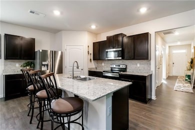 Kitchen with backsplash, stainless steel appliances, dark wood-style floors, and recessed lighting