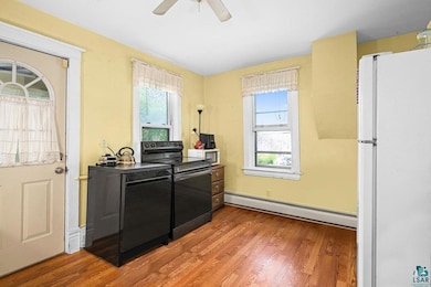Kitchen featuring freestanding refrigerator, electric stove, baseboard heating, and plenty of natural light