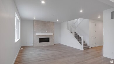 Unfurnished living room with stairway, a fireplace, light wood-style flooring, and recessed lighting