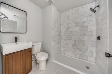 Bathroom with vanity, toilet, a tile shower, and t