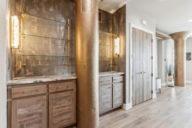 Bar with light wood-type flooring and ornate colum