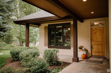 View of exterior entry with a porch, a shingled roof, and stucco siding