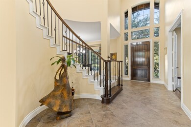 View showing the two-story foyer entry with tons of windows allowing in natural light and the grand staircase with wrought iron spindles.