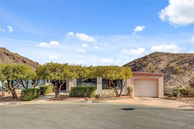 View of property hidden behind natural elements with driveway, a mountain view, stucco siding, and a garage