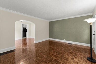 Unfurnished room featuring arched walkways, baseboards, and crown molding