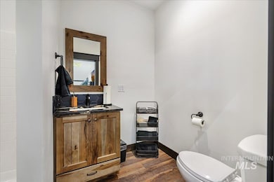 Half bath with vanity, dark wood finished floors, and backsplash