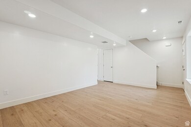 Finished below grade area with light wood-style flooring and recessed lighting