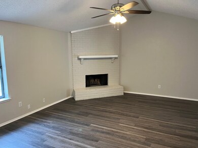 Unfurnished living room featuring a textured ceiling, a ceiling fan, dark wood finished floors, and a fireplace