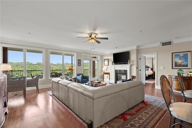 Living room featuring crown molding, baseboards, a premium fireplace, ceiling fan, and healthy amount of natural light