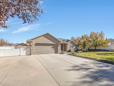 Ranch-style house featuring concrete driveway, a gate, stone siding, stucco siding, and an attached garage