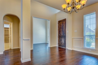 Foyer entrance featuring dark wood-style flooring, arched walkways, and a chandelier