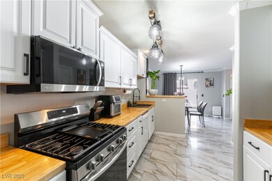 Kitchen with gas range, a sink, white cabinets, li