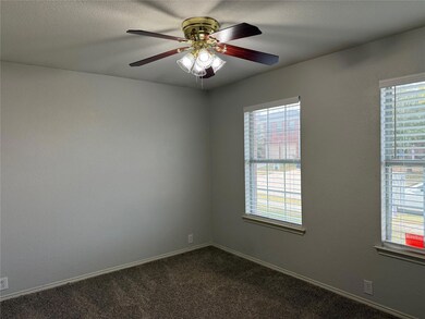 Empty room with dark colored carpet, a textured ceiling, and ceiling fan