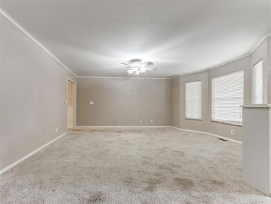 Carpeted empty room with crown molding, ceiling fan, and baseboards