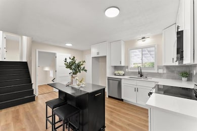 Kitchen featuring a kitchen breakfast bar, electric range oven, light wood-style floors, and tasteful backsplash